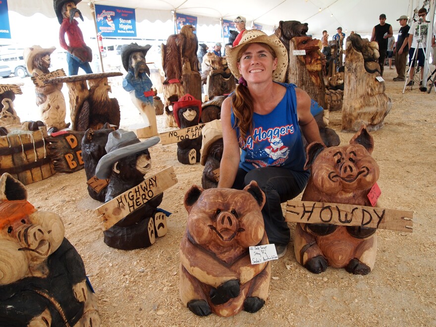 Chainsaw artist Sandy Songer of Broken Bow, Oklahoma, poses with some of her works.