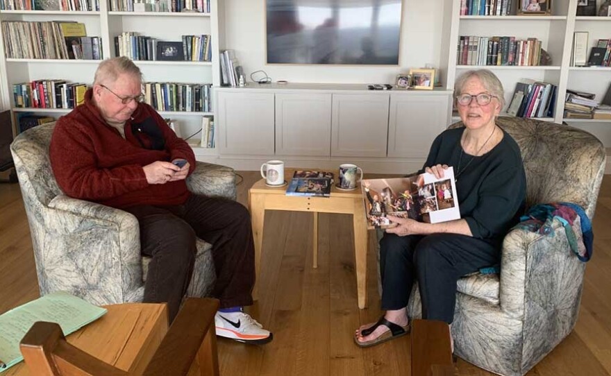 Marilyn Shea-Stonum (right) holds up a photo album containing pictures of her granddaughter, Kennedy, while her husband Gary looks at pictures on his phone.