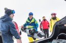 People unloading skis and snowboards from a car.