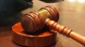 A wooden gavel resting on a stand on a wooden table.
