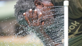 Paul Williams cools off in water while taking a break from yard work in Richardson.