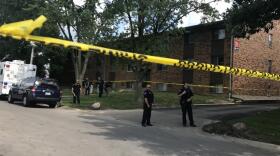 A biulding cordoned off with yellow tape and police officers standing outside.