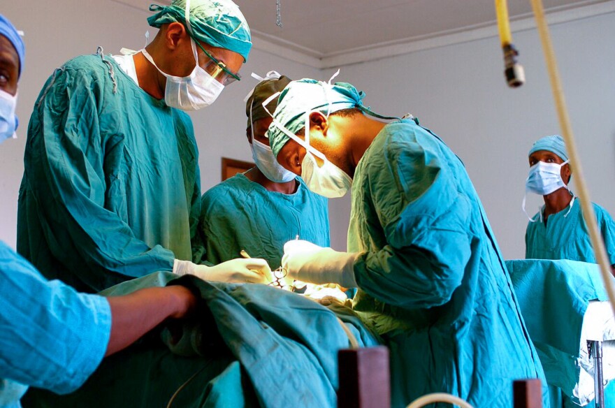 Dr. Dilan Ellegala, left, supervises Dr. Emmanuel Nuwas of Tanzania as he inserts a shunt in a baby with hydrocephalus. Ellegala has played a key role in training local doctors, as described in the new book A Surgeon in the Village. Early on, he trained a hospital staffer who wasn't a doctor to do brain surgery.