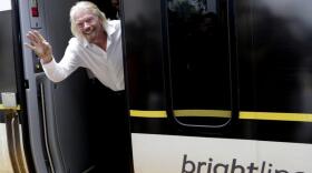 Richard Branson, of Virgin Group, waves as he arrives on a Brightline train in West Palm Beach, Fla.