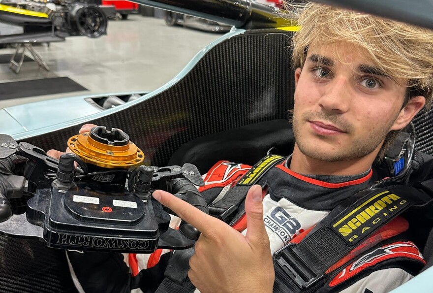 Young man with blond hair in a race car. 