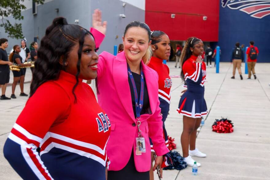 Chelsea Torres, in the pink jacket, tries to cool off cheerleaders as they greeted students at American High School in Hialeah on the first day of the school year for Miami-Dade County Public Schools.