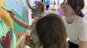 Artist Lacy Hale works with children who survived last July's floods in Floyd County on a mural she designed.