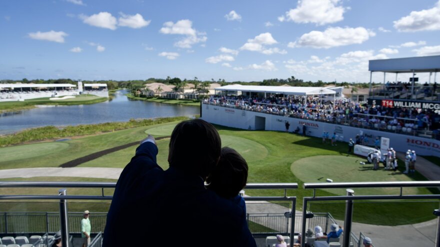 Gov DeSantis and his child are in silhouette. The governor is pointing to something on a golf course. 