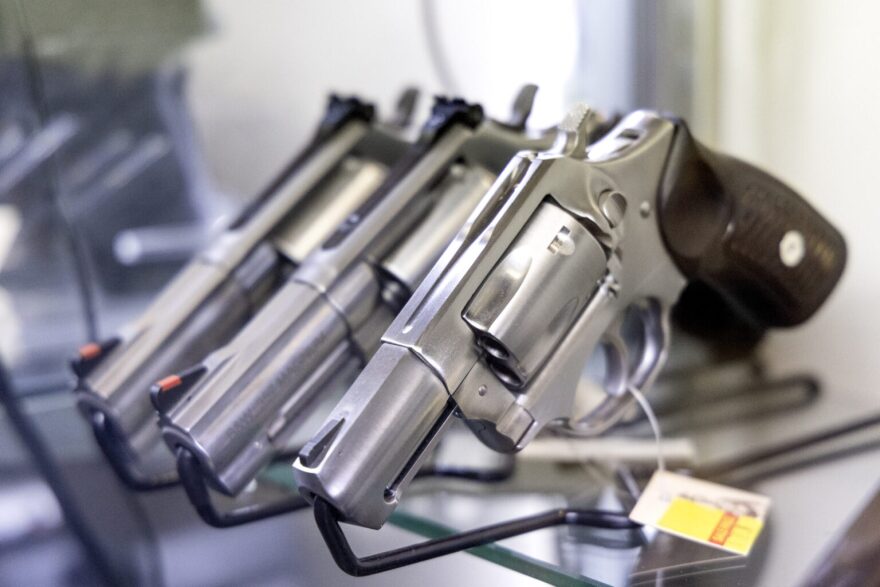 Three guns on a rack with price tags