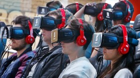 Visitors wear virtual reality glasses to watch a show on the first public day at the IAA car show in Frankfurt, Germany, Saturday, Sept. 16, 2017. (Michael Probst/AP)