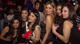 A group of women holding drinks pose for a picture.
