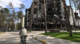 A local resident rides next to a destroyed residential building in Irpin, northwest of Kyiv amid the Russian invasion of Ukraine.