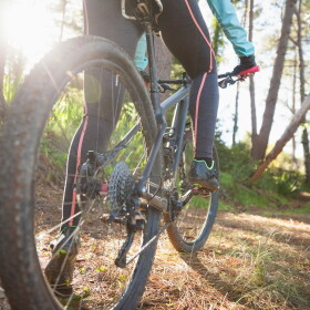 Low section of female mountain biker riding bicycle