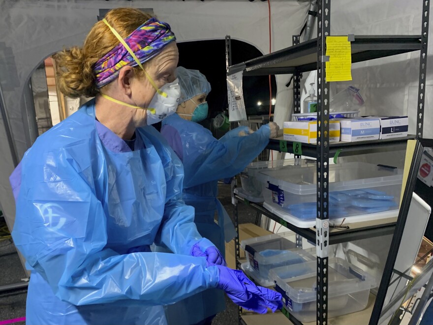 Nurse Chris Rutledge suits up in personal protective equipment before entering the patient wards of a COVID-19 field hospital, Friday, Jan. 15, 2021, in Lenoir, N.C.