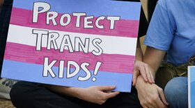 A protester holds a poster calling for lawmakers to protect trans children by voting against House Bill 1125, which would ban gender-affirming care for trans children at the Mississippi Capitol in Jackson, Wednesday, Feb. 15, 2023.