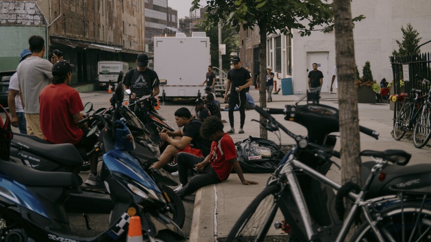 Migrants at the Clinton Hill Shelter seek relief from the overcrowded confinements of 47 Hall St. Residents working as delivery drivers wait for orders to come in on July 19 in Brooklyn, N.Y.