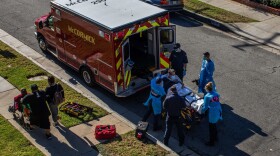 After administering him with oxygen, County of Los Angeles paramedics load a potential COVID-19 patient in the ambulance before transporting him to a hospital in Hawthorne, California on Dec. 29, 2020 as a family walks by. (Apu Gomes/AFP via Getty Images)
