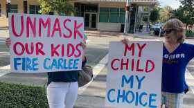 Protesters hold signs expressing opposition toward the Alachua County Public Schools employee and student mask mandates before a school board meeting on Sept. 7. (Abigail Hasebroock/WUFT News)
