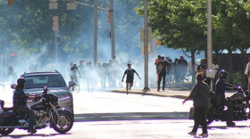 Demonstrators flee tear gas at the corner of New York Street and Capitol Ave.