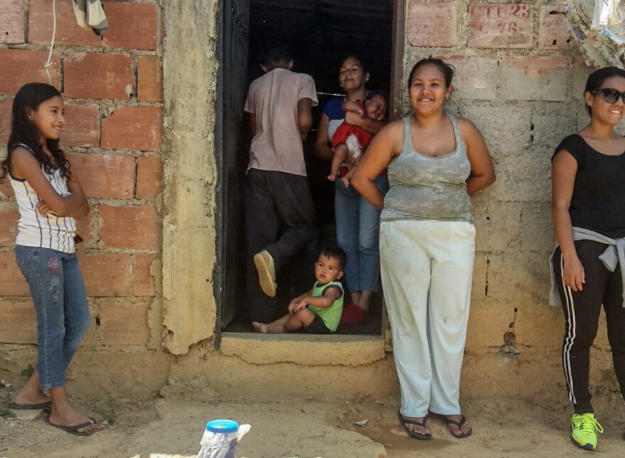 Raquel Castaño stands to the right of the entrance to her home in Ramo Verde, a poor neighborhood on the outskirts of Caracas, Venezuela, is a mother of five. She says her 15-year-old son often skips school to work delivering water to the community.