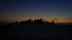 The sun sets behind the West Bay skyline in Doha, Qatar, Monday, Nov. 28, 2022. (AP Photo/Matthias Schrader)