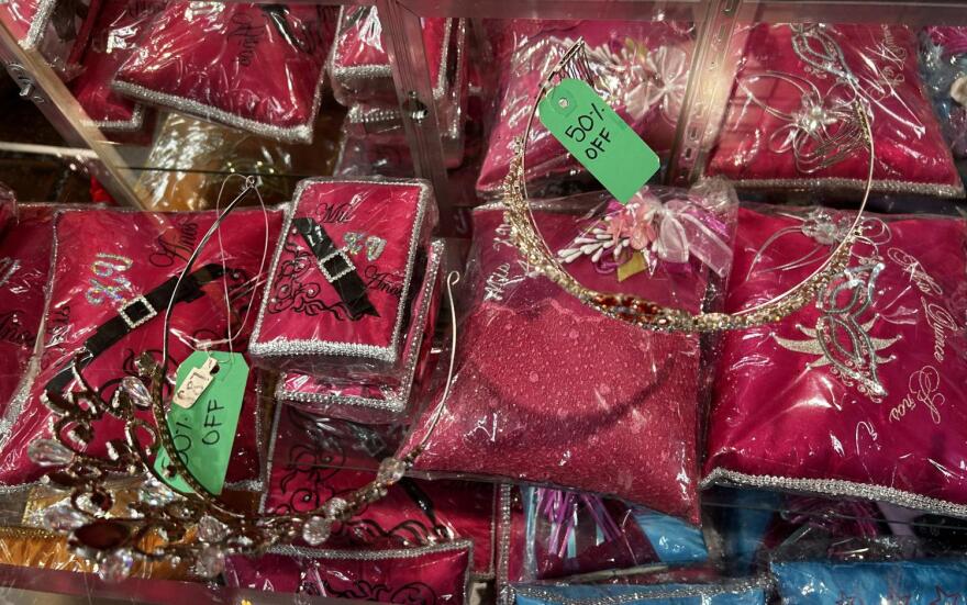 Two special occasion tiaras are seen with tags that read "50% off" on top of a glass case that holds other accessories.