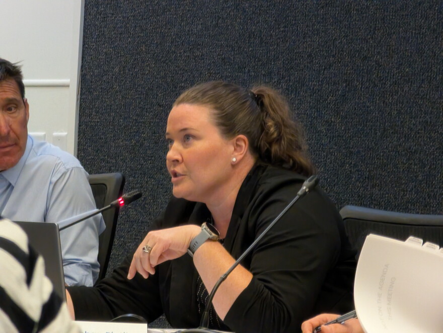 A woman sitting at a table speaking into a microphone