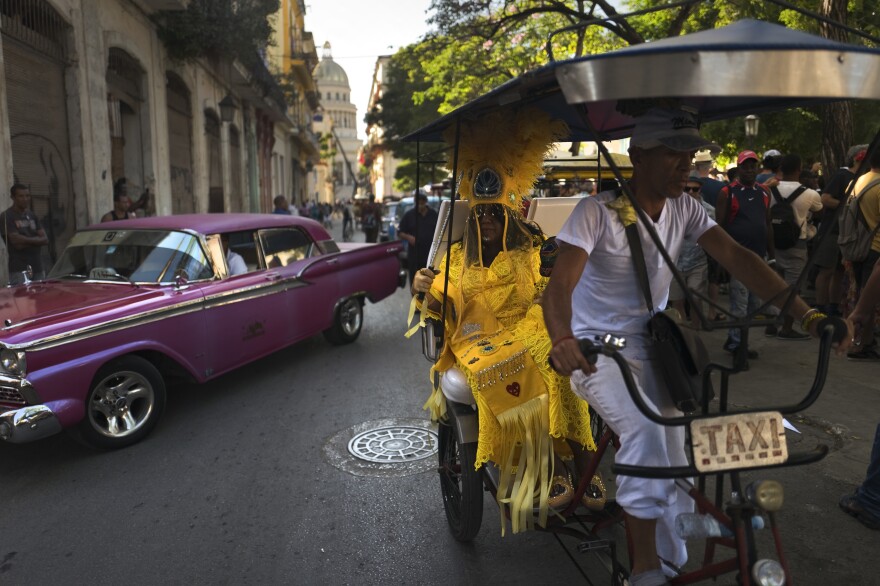 Cherice Harrison-Nelson, the Big Queen of the Mardi Gras Indians group the Guardians of the Flame, sits in traffic on a taxi bike.