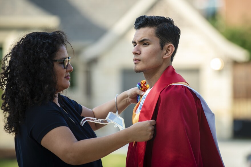 Xochitl Ortiz ayuda a su hijo Izcan Ordaz a probarse su traje de graduación frente a su casa en Fort Worth, Texas.