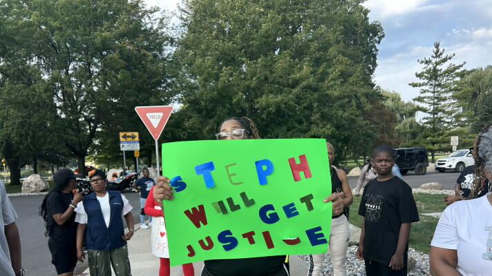 A woman displays a "Step will get justice" sign near Ojibway Park in Saginaw, Mich. on Monday, Aug. 31, 2026 ahead of the Saginaw city council meeting.