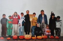 A group of children in costumes stand in front of carved pumpkins at Halloween time.