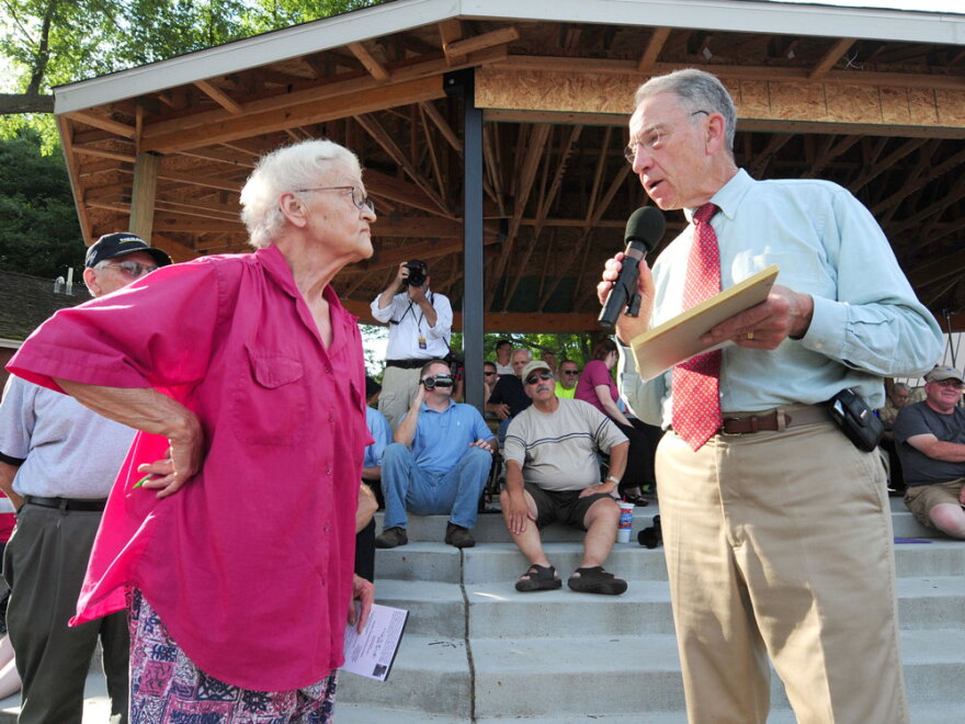 Sen. Chuck Grassley (R-IA) responds to a question from Sheryl Prather at a town meeting in Adel, Iowa. Facing heat from conservative constituents, the senator has backed away from bipartisan health care negotiations.