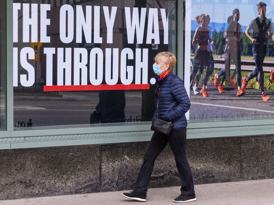 A person wearing a face mask walks down a mostly empty Michigan Avenue in Chicago Thursday. In all major political groups, most people say they support shelter-in-place orders to fight the COVID-19 pandemic, according to a recent poll.