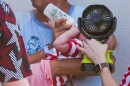 A woman holds a fan in front of a bottle-fed baby at the Great American State Fair during an extreme heat wave, Friday, July 3, 2026, on the National Mall in Washington.
