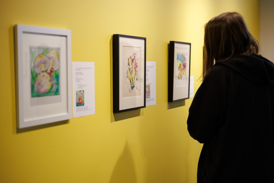 Woman looks at images on wall in the exhibit “The Sweet and Sour Journey of Langston Hughes and Elmer W. Brown” on view at ARTneo in Cleveland.