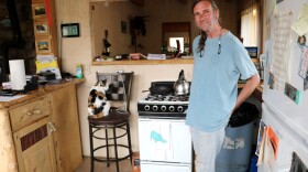 David Moore with his cat, Lucy, in the kitchen of his home in a rural, mountainous region of Bellvue, Colorado on May 31, 2023. Moore was surprised to see the county had nearly tripled his property valuation for 2023. It was later adjusted downward.