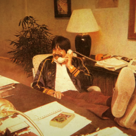 Throwback photo of David Marsden at a desk with his feet up, talking on a landline phone.