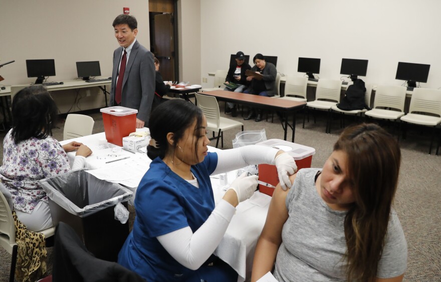 Dr. Philip Huang, left, director of Dallas County Health and Human Services, checks in with health workers during an influenza vaccine event at Eastfield College in Mesquite, Texas, Thursday, Jan. 23, 2020.