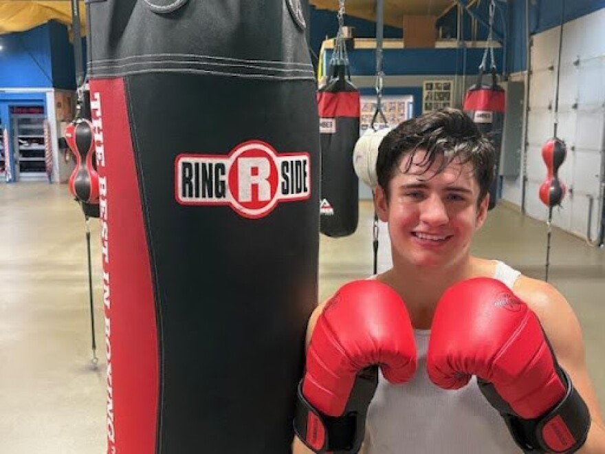 Alex Ziouras smiles beside a heavy bag during training at Crown Boxing Club in Lansing.
