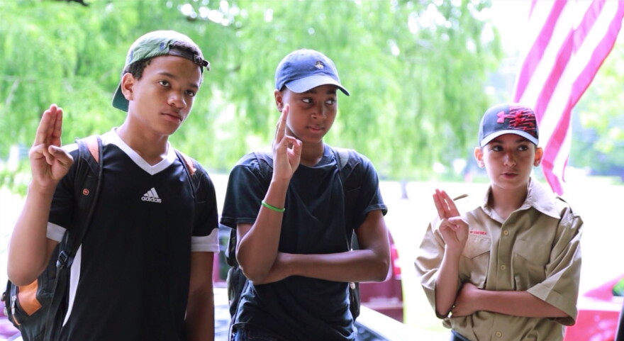 Members of Troop 2690 give the Scout sign and salute. (Gabriel Kramer/WCPN ideastream)