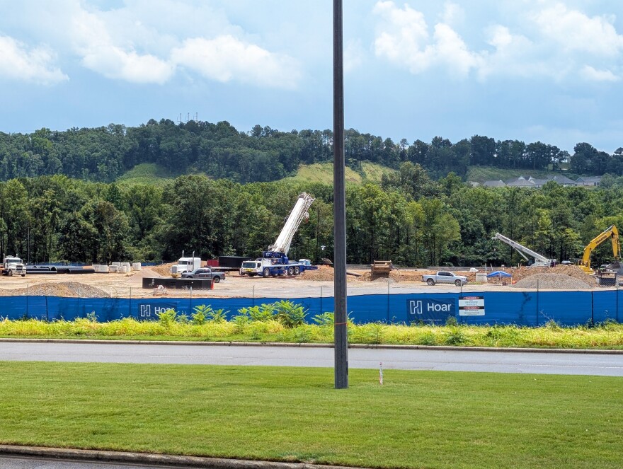 Construction equipment is visible behind a blue fence surrounding the Nebius data center construction site.