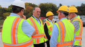 Dan Kildee wearing a safety vest speaking to 4 other men also wearing safety vests and hard hats