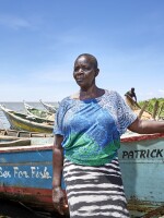 Justine Adhiambo Obura, chairwoman of the No Sex For Fish cooperative in Nduru Beach, Kenya, stands by her fishing boat. Patrick Higdon, whose name is on the boat, works for the charity World Connect, which gave the group a grant to provide boats for some of the local women.