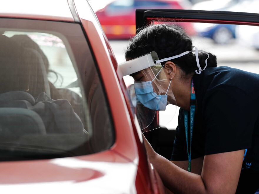 A Health worker administers vaccinations at a pop-up drive-in clinic Monday, Oct. 11, 2021, in Auckland, New Zealand. New Zealand's doctors and teachers are among those who must soon be fully vaccinated against the coronavirus to continue working in their professions, the government announced Monday.