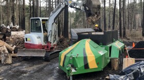 Forest restoration workers outside Vida put sawed up timber into an air curtain incinerator to produce biochar.