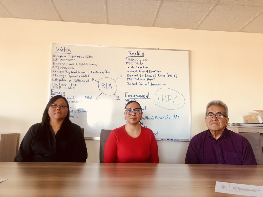 Colleen Friday, Letara Lebeau, and Wes Martel sit at a table in front of a whiteboard.