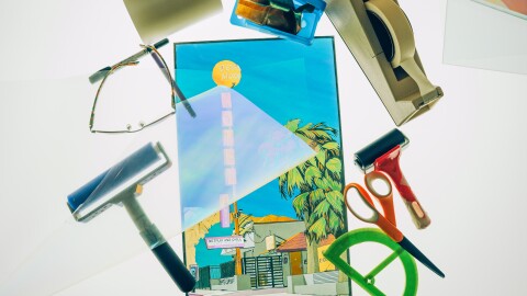 A polage image of a historical motel sits on a table surrounded by art materials.