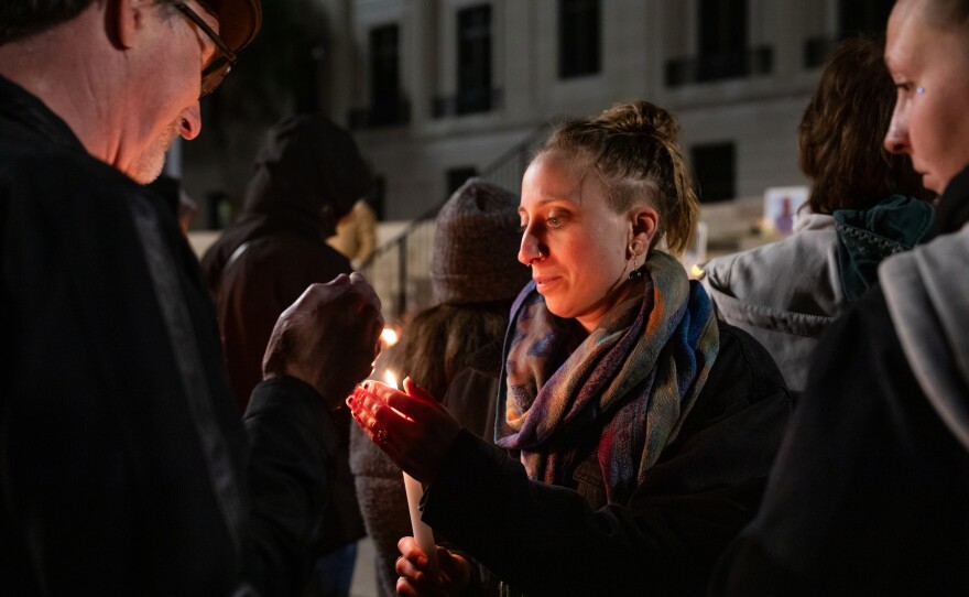 A community member lights a candle during a vigil for Renee Good and other victims of ICE violence outside the Alton Lennon Federal Building in downtown Wilmington on January 14, 2025. Community members listened as organizers with Siembra NC and elected officials spoke and honored the victims.