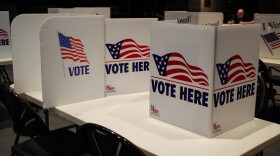 Vote here signs sit on top of white folding tables