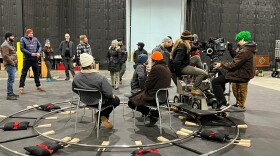 A group of people in a circle with film equipment in a film studio.
